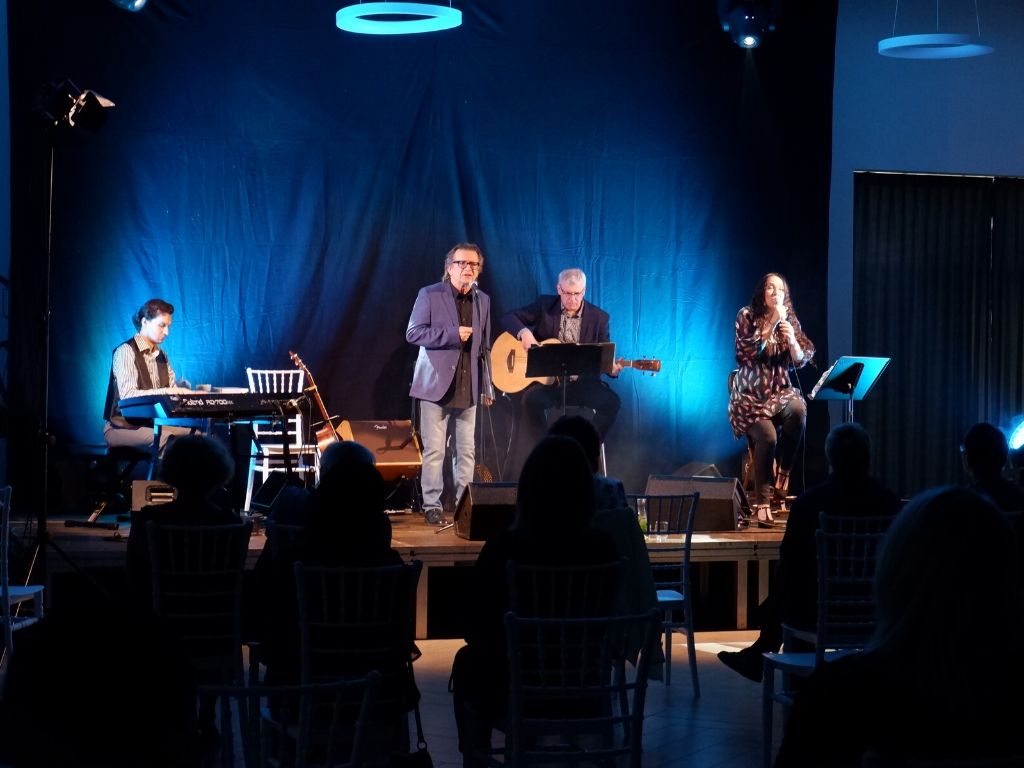 Na scenie czterech artystów: dwie osoby śpiewają, jedna gra na klawiszach i jedna na gitarze