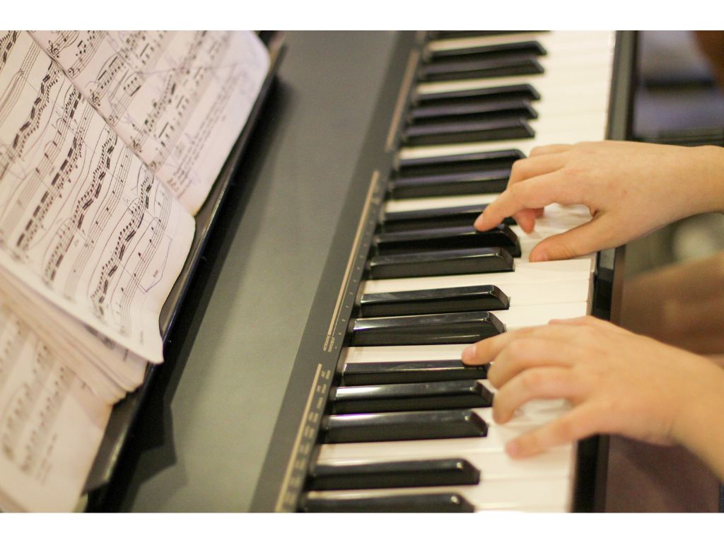 Klawisze pianina, na których widać dłonie.