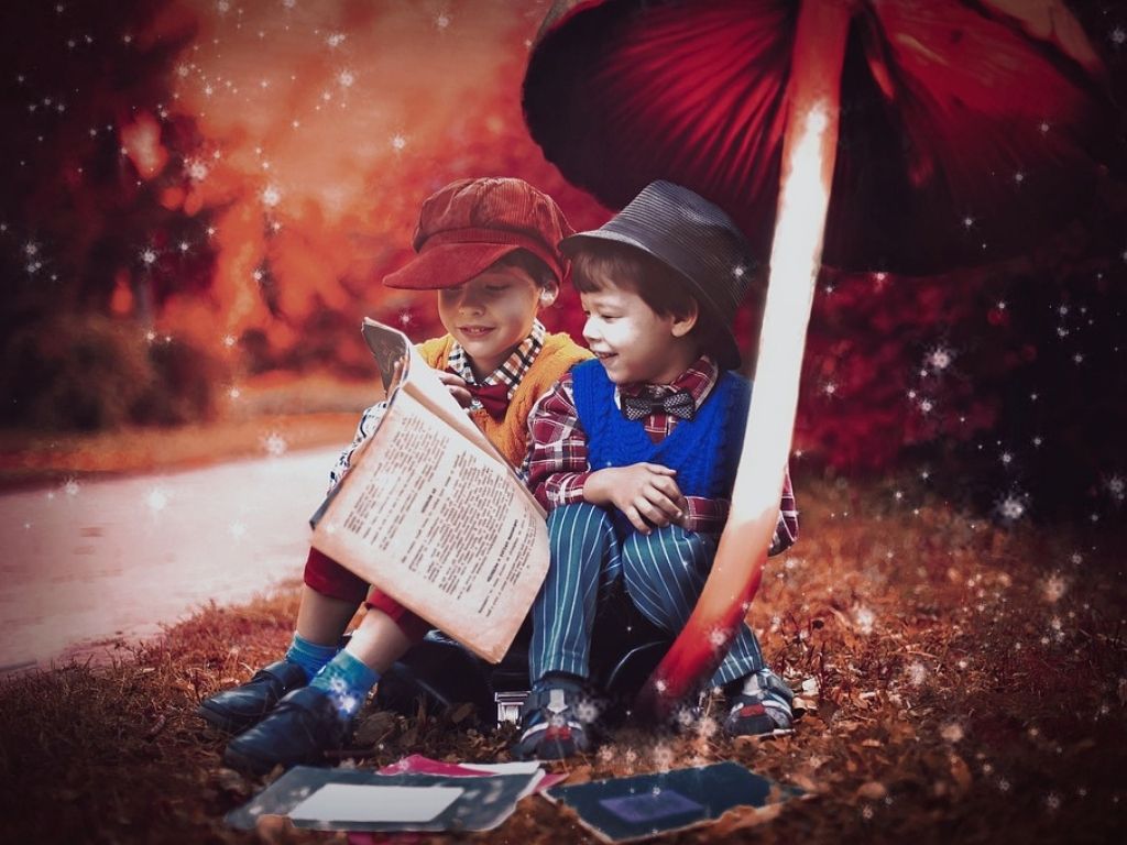 Dwóch chłopców siedzi pod dużym grzybem i czyta książkę.